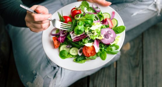 a-person-sitting-on-the-floor-eating-a-healthy-salad